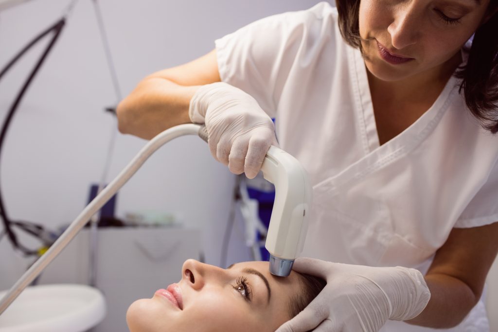 Female patient getting facial laser treatment at dermatology clinic