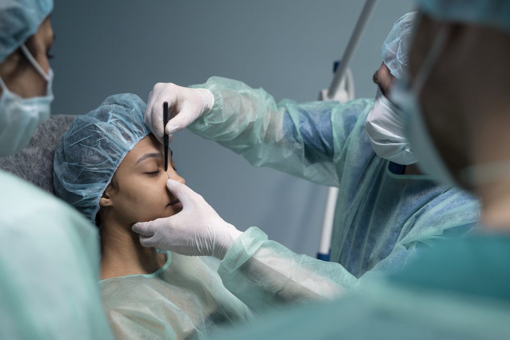 Doctor performing nose job surgery procedure on patient